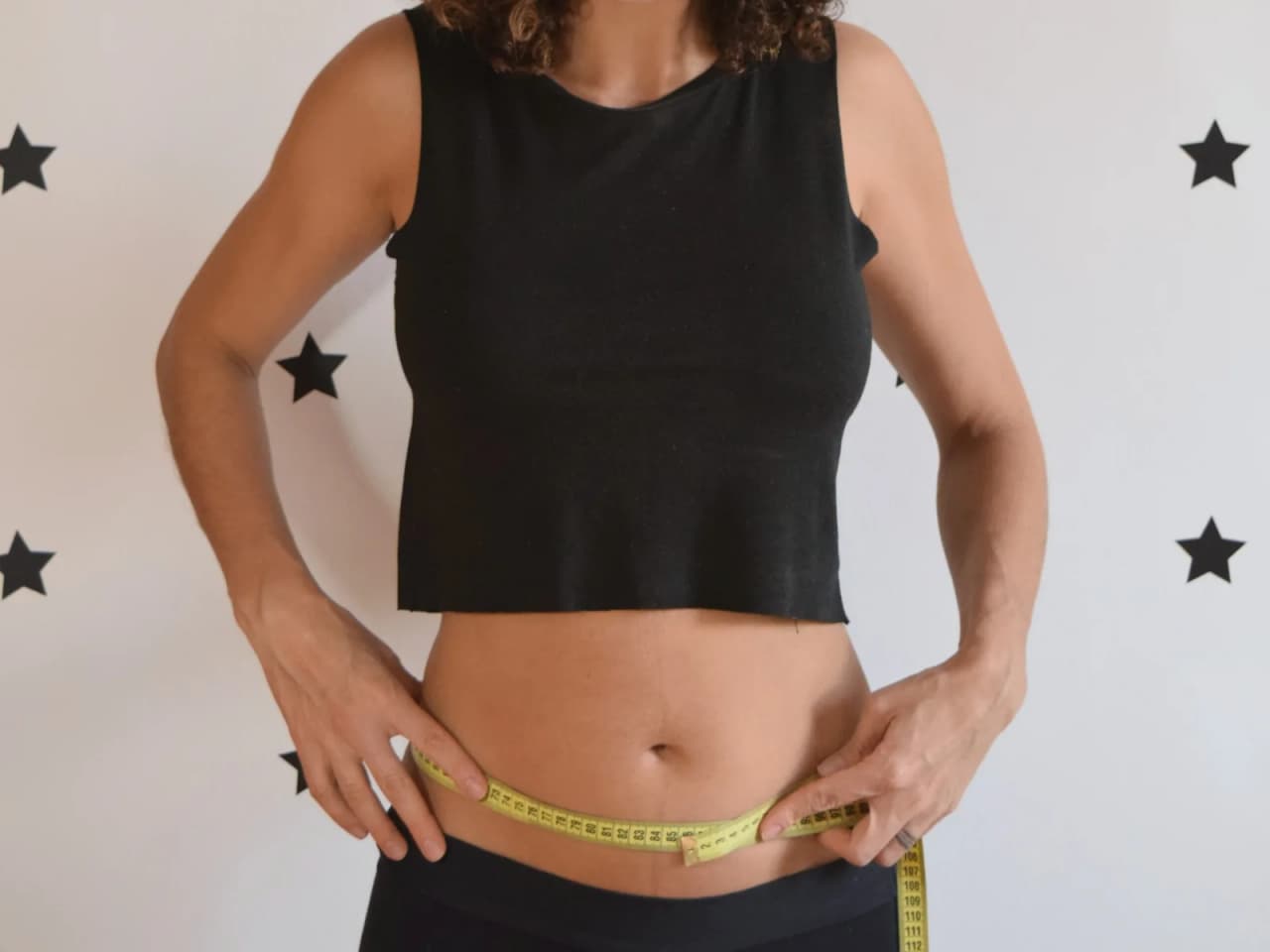 Cláudia Heringer mede a própria cintura com fita métrica no pós-parto